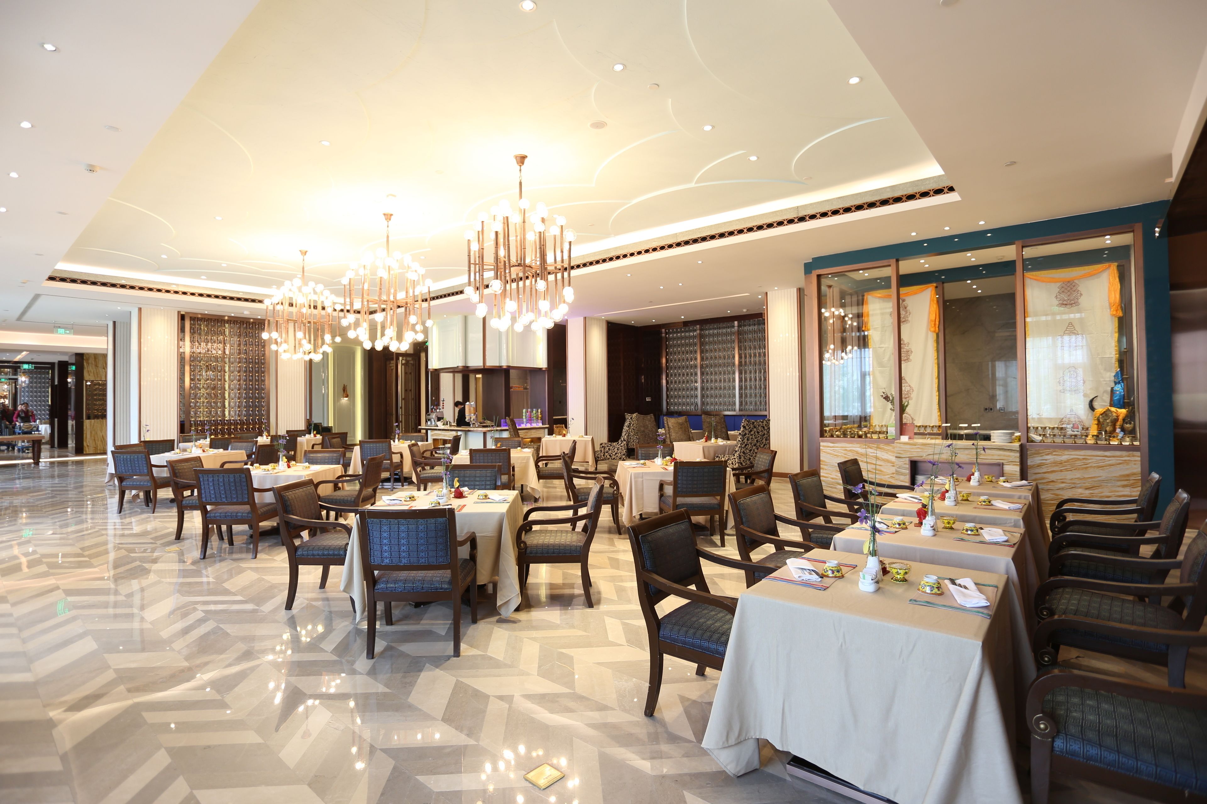 Un comedor amplio con varias mesas y sillas, candelabros elegantes y un suelo pulido.