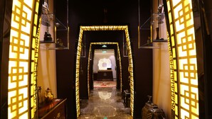 A corridor with a geometric patterned door frame, a marble floor, and a small table with a decorative item on the left. - Xizang Hotel Chengdu (Chengdu)