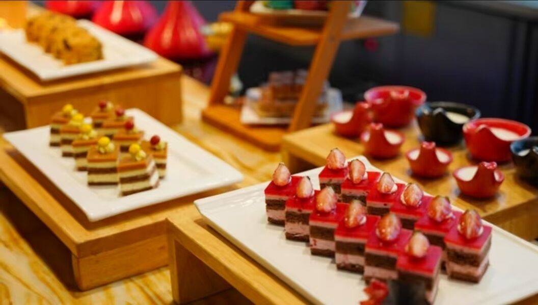 A buffet with various desserts and a selection of red teapots.