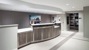 A modern reception area with a curved reception desk, a digital display, and a wall-mounted photo. - Residence Inn by Marriott Kansas City Country Club Plaza (Kansas City)