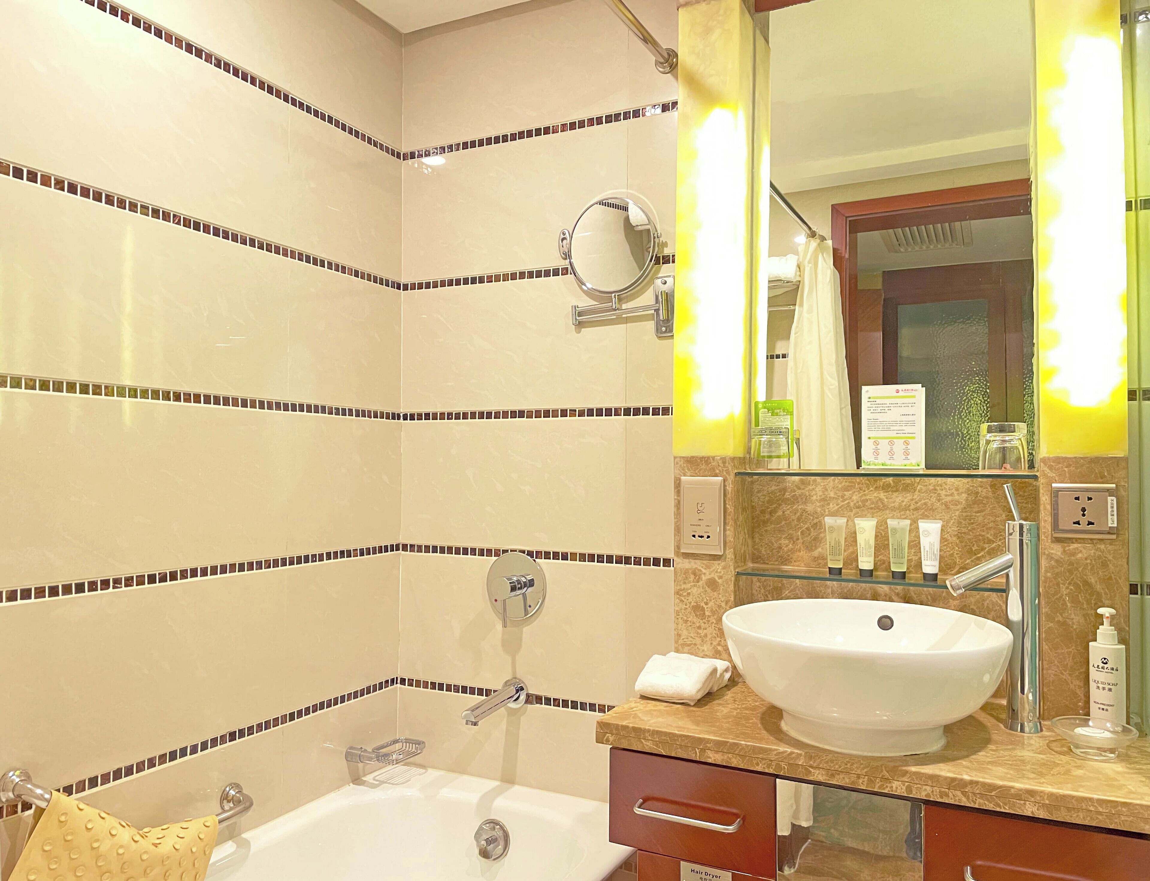 Un baño con bañera, lavabo, espejo y artículos de aseo sobre el mostrador.