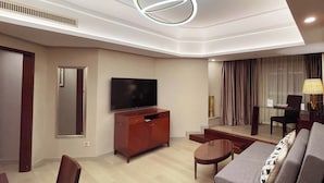 A modern living room with a flat-screen TV, wooden furniture, a glass coffee table, and a unique circular ceiling light. - Merry Hotel Shanghai (Shanghai)