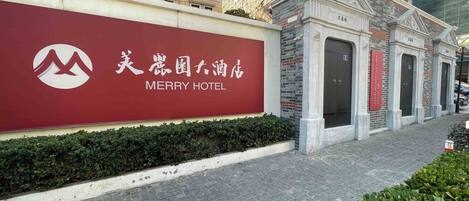 A hotel entrance with a large sign reading "MERRY HOTEL" and a traditional architectural facade.