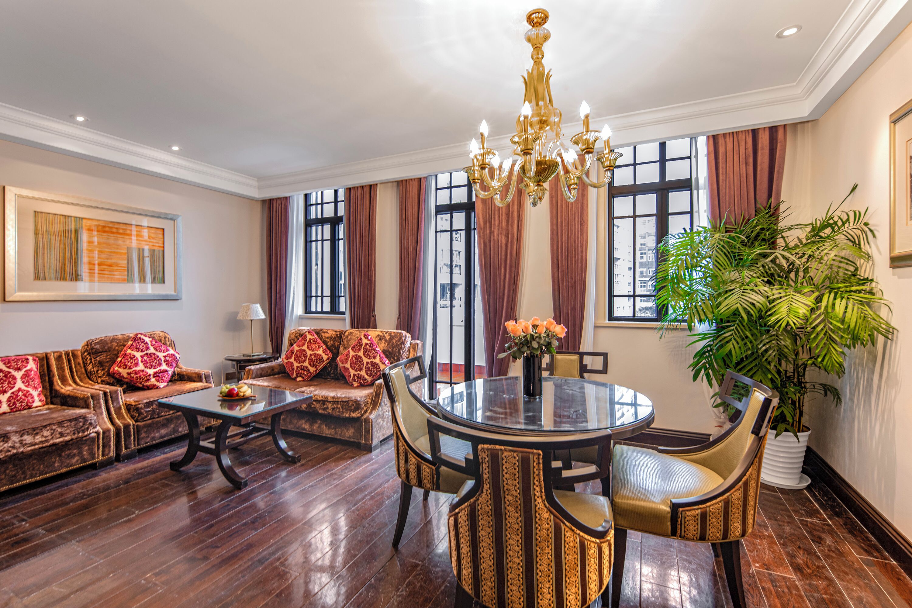 A spacious living room with a round dining table, comfortable sofas, and a large potted plant.