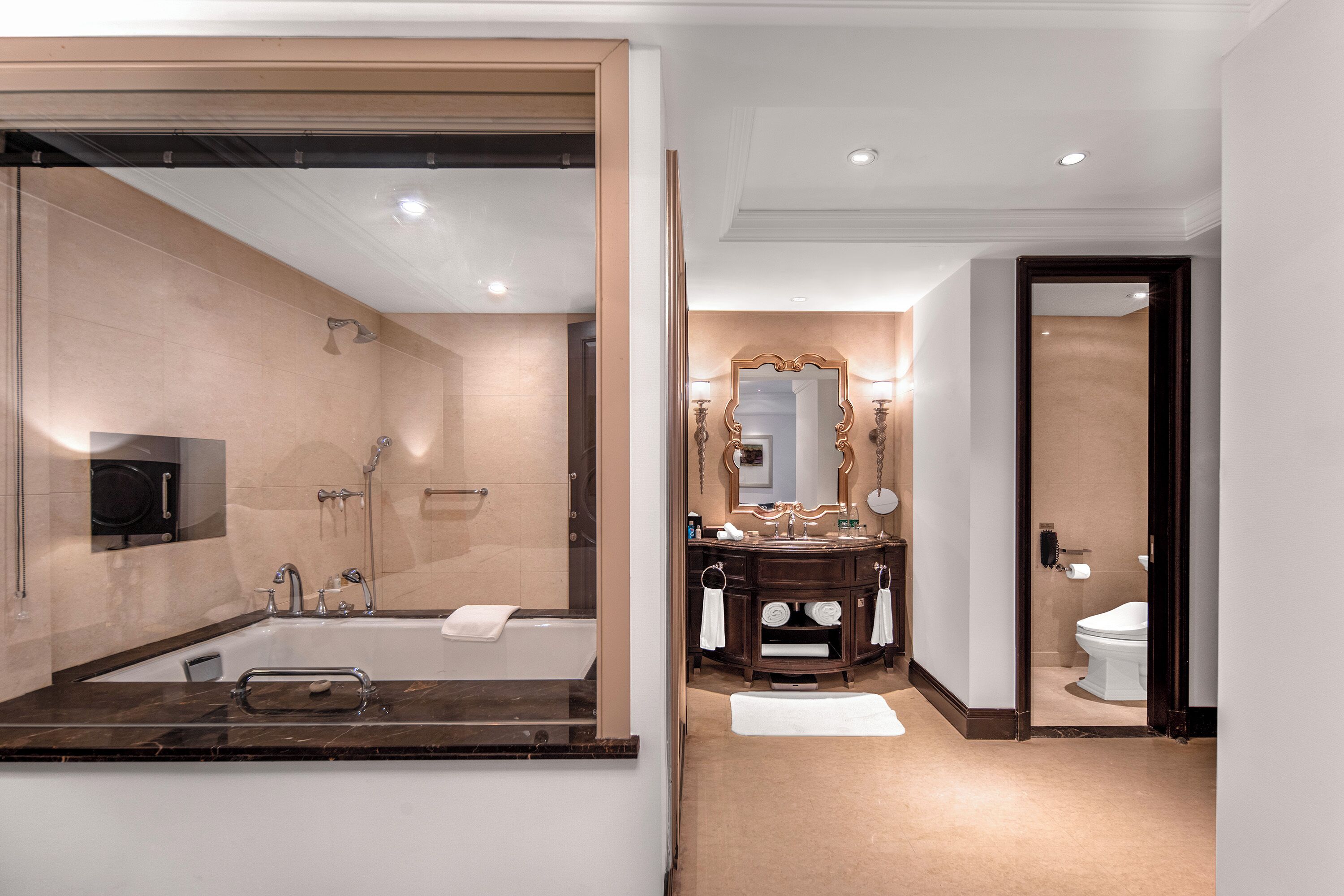 Un baño moderno con un espejo grande, una bañera, un lavabo y un inodoro.