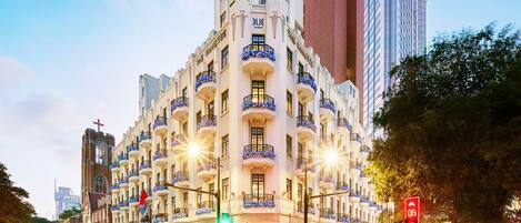 A multi-story hotel with balconies, a restaurant entrance, and a street view with traffic lights and vehicles.