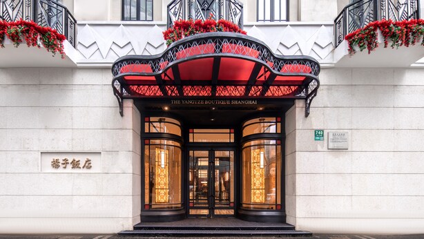 La entrada del The Yangtze Boutique Shanghai, con un toldo negro, flores rojas y un letrero que indica la dirección.