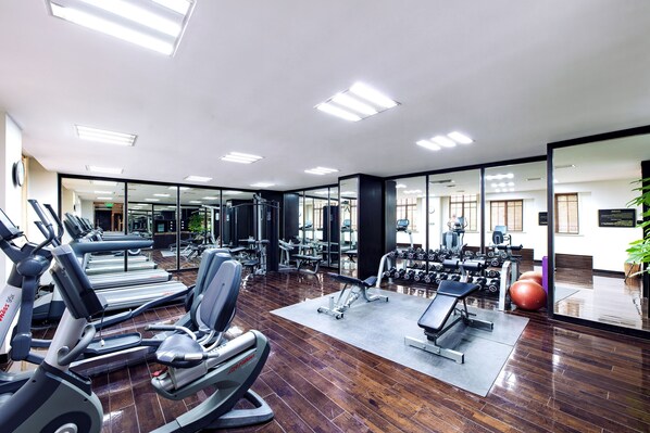 Un gimnasio con cintas de correr, máquinas de pesas y pesas sueltas.