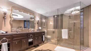 Un baño moderno con un espejo grande, tocador de madera oscura y ducha con mampara de vidrio.