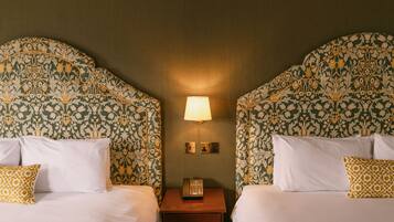 A hotel room with two beds, a nightstand with a lamp, and a telephone.