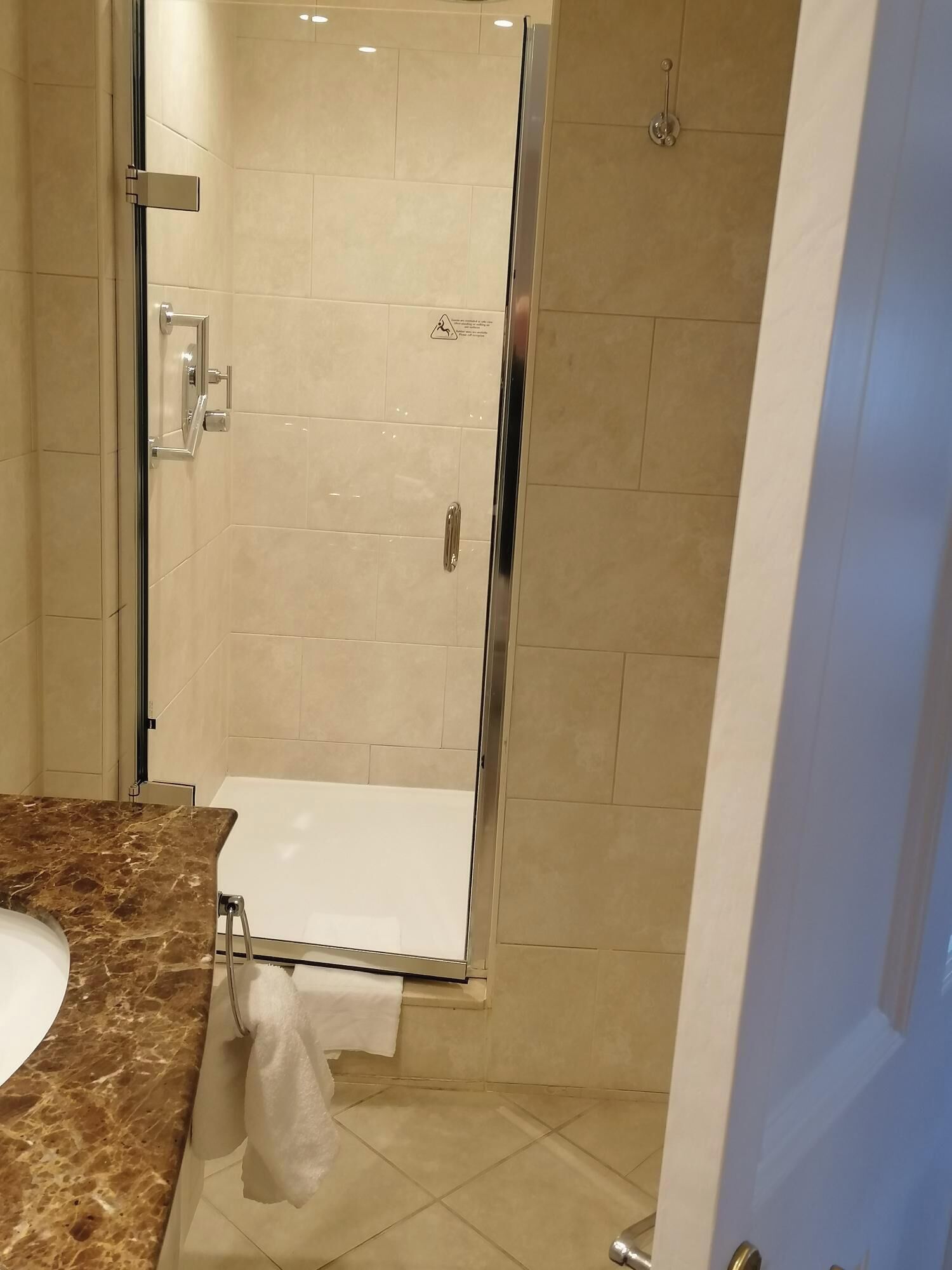A modern bathroom with a glass-enclosed shower, a marble countertop, and a white sink.