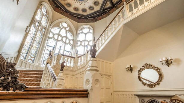 Una gran escalera con barandales ornamentales y un techo decorativo.