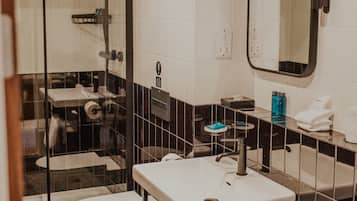 A bathroom with a glass-enclosed shower, a white toilet, a sink with a mirror, and a towel rack.