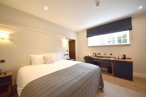 Une chambre d’hôtel avec un grand lit, un bureau et une fenêtre avec des stores.
