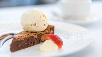 A dessert plate with a slice of cake topped with a scoop of ice cream and a strawberry.