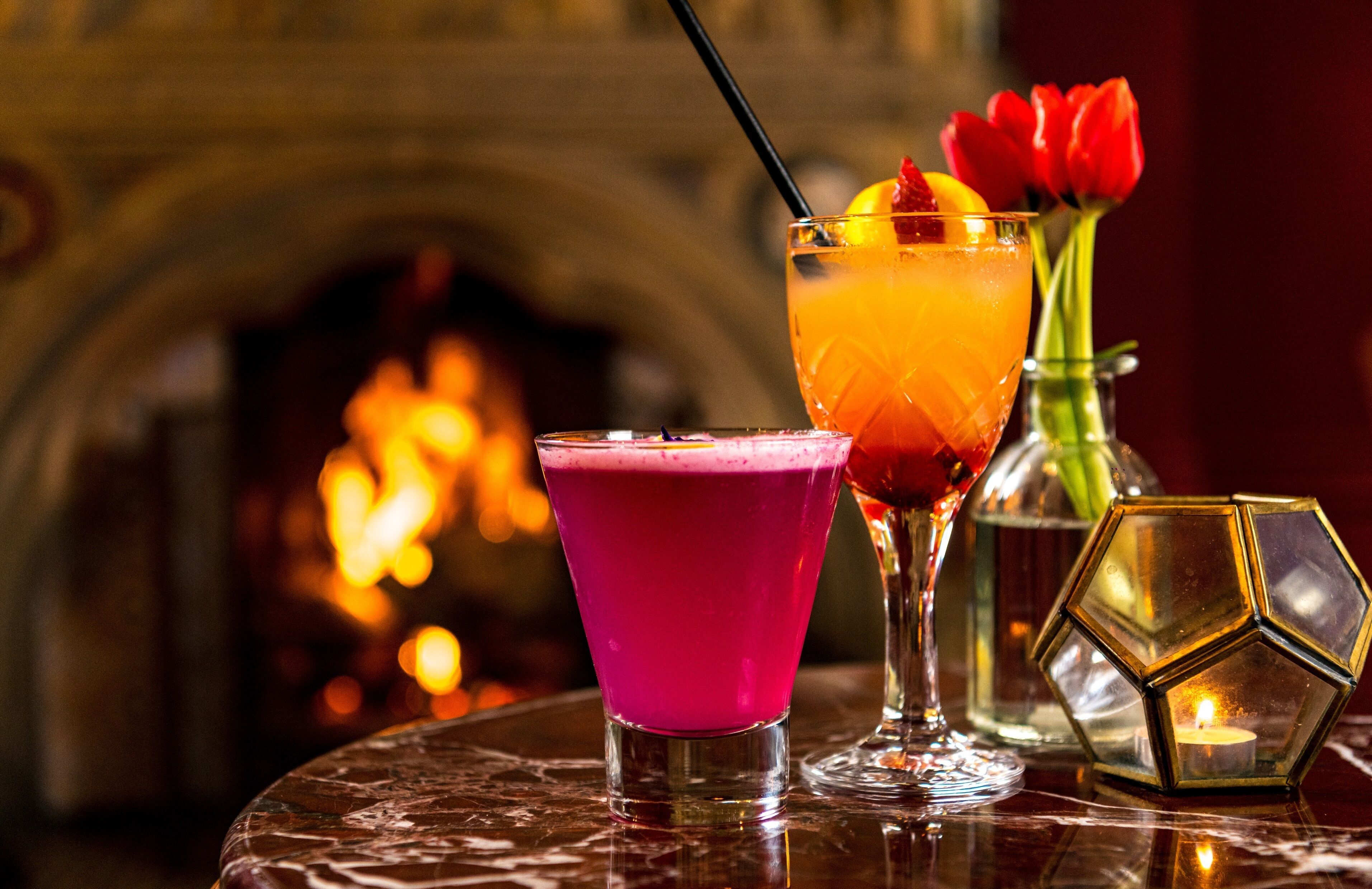 Deux cocktails sur une table, avec une cheminée en arrière-plan.