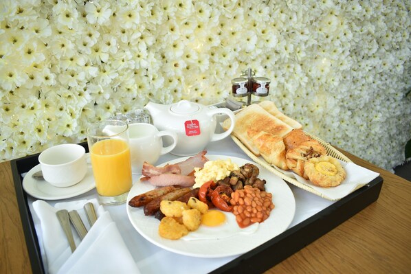 A breakfast tray with eggs, bacon, beans, toast, and juice.