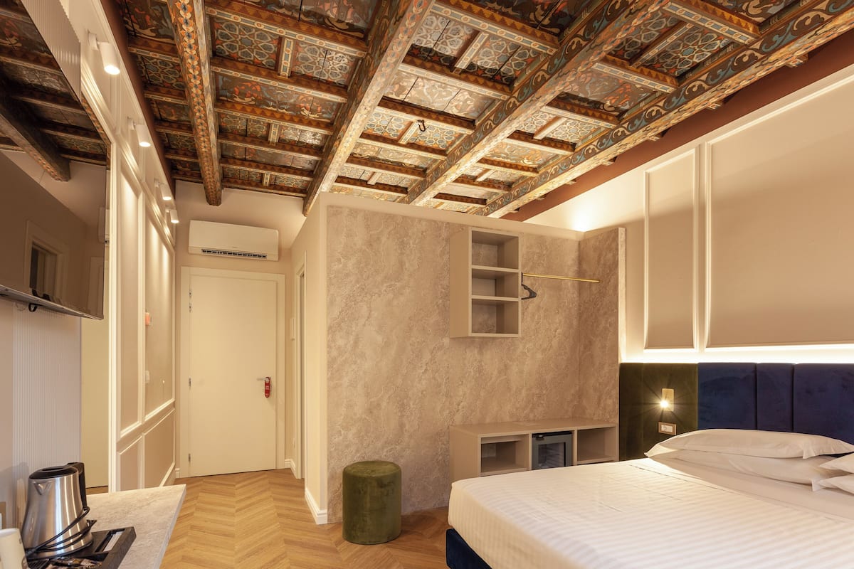 Una camera da letto moderna con un letto grande, un armadio a muro, un angolo salotto e un soffitto decorato.