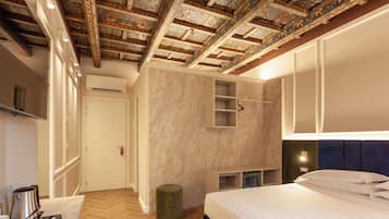 A modern bedroom with a large bed, a built-in wardrobe, a small seating area, and a decorative ceiling.