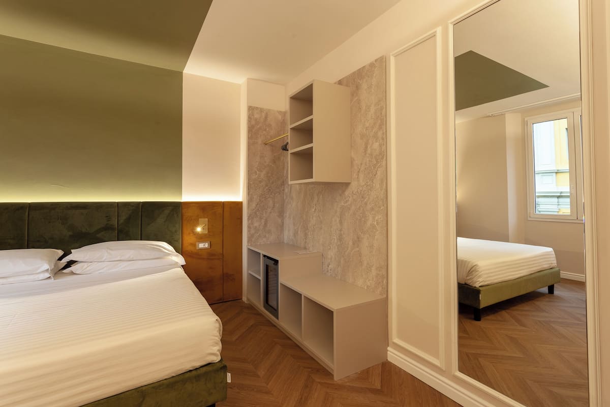Una camera da letto con un letto, una TV integrata e uno specchio.