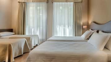 Una habitación de hotel con dos camas, cada una con cabecero, y una mesita de noche con lámpara.