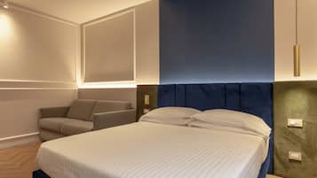 Una habitación de hotel moderna con una cama grande, un área de descanso con sofá e iluminación en la pared.