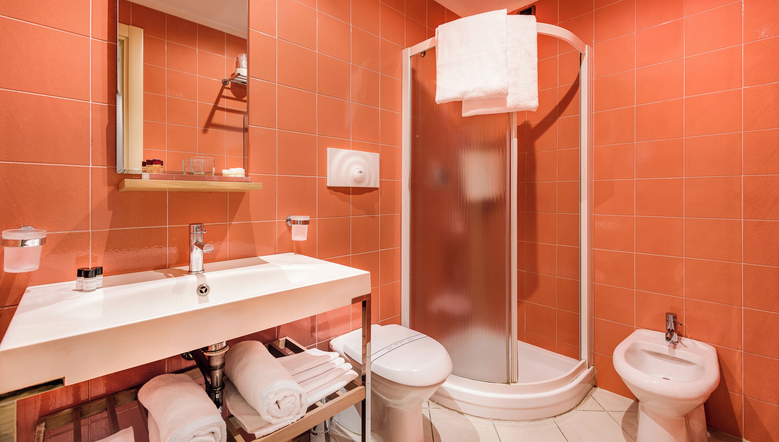 A bathroom with a white sink, a toilet, a bidet, and a glass-enclosed shower.