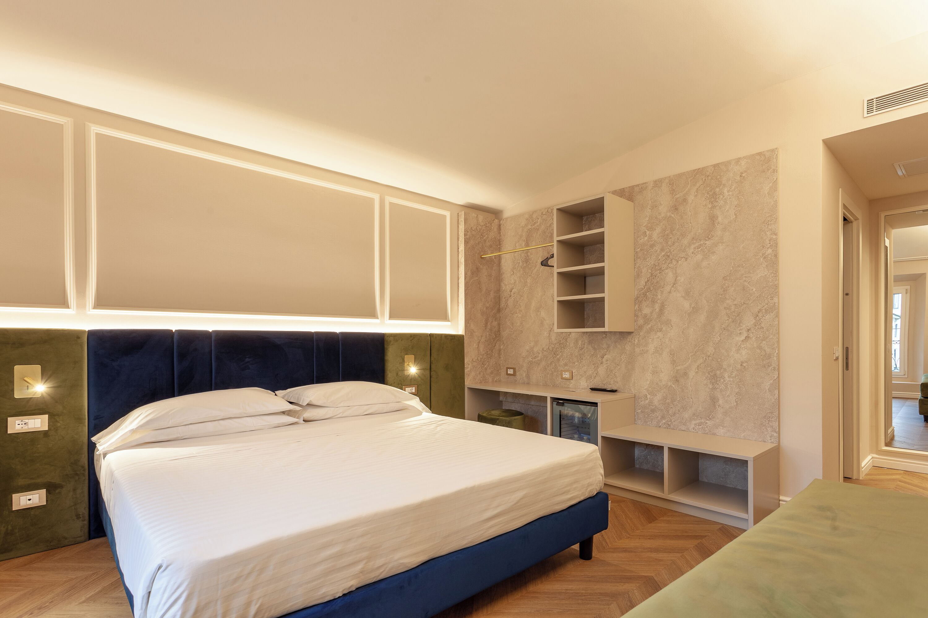 A bedroom with a large bed, built-in shelving, and a vanity with a mirror.