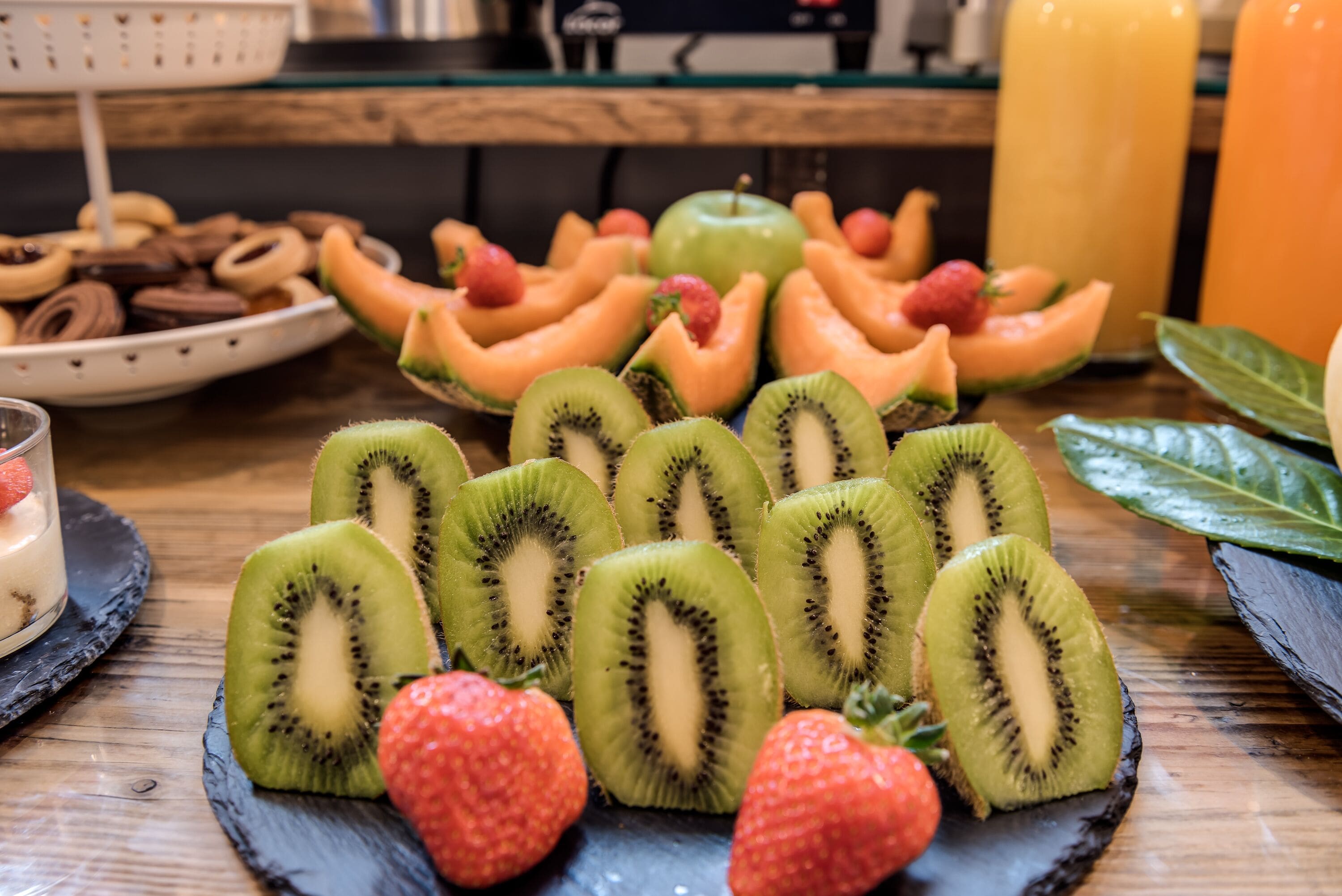 Una mesa con kiwi en rodajas, fresas y trozos de melón.