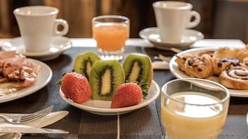 A breakfast setting with plates of food, a glass of orange juice, and two cups of coffee.