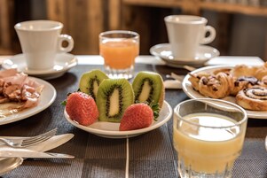 A breakfast setting with plates of food, a glass of orange juice, and two cups of coffee.