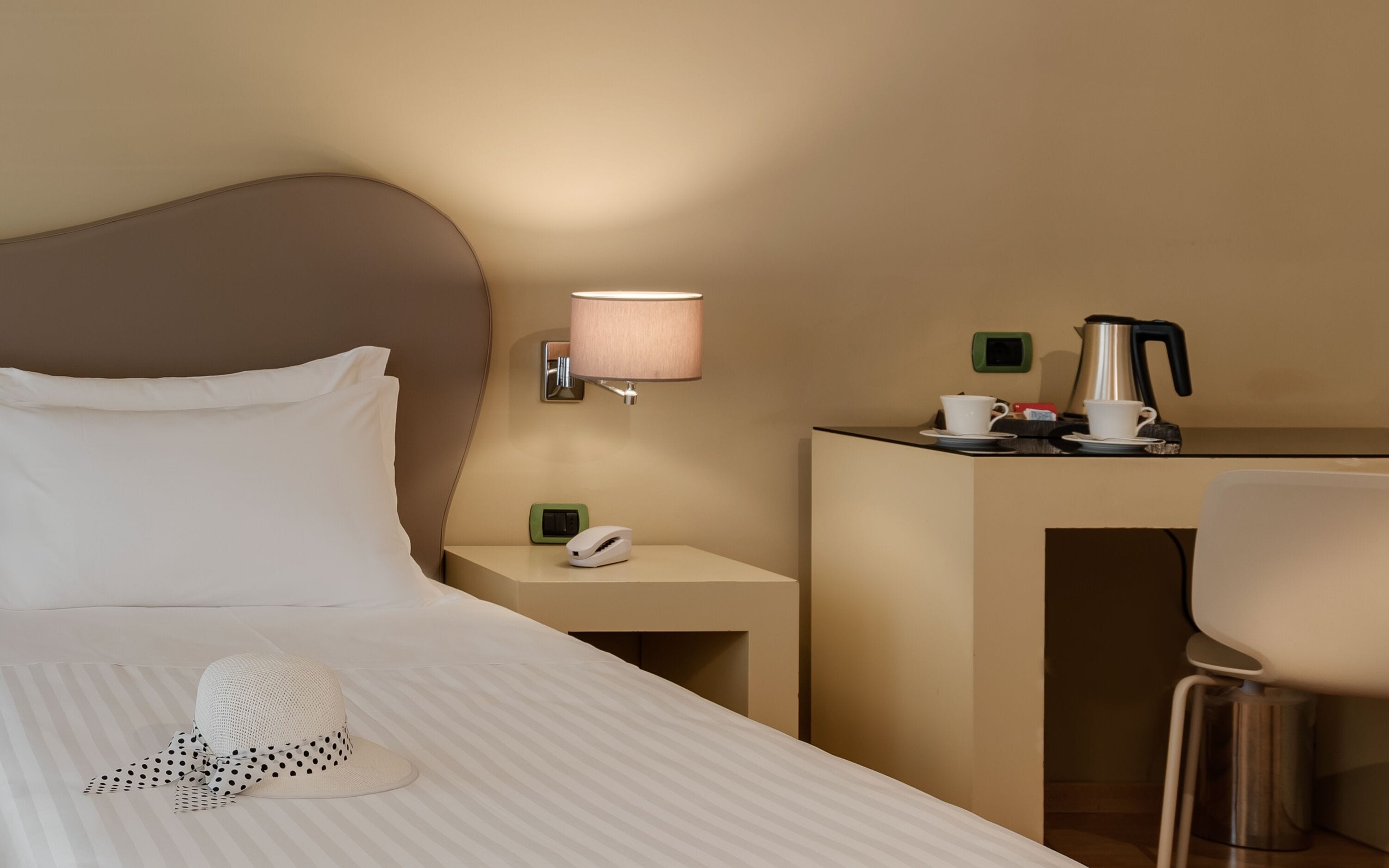 Une chambre d’hôtel avec un lit bien fait, une table de chevet avec une lampe, une machine à café et un téléphone.