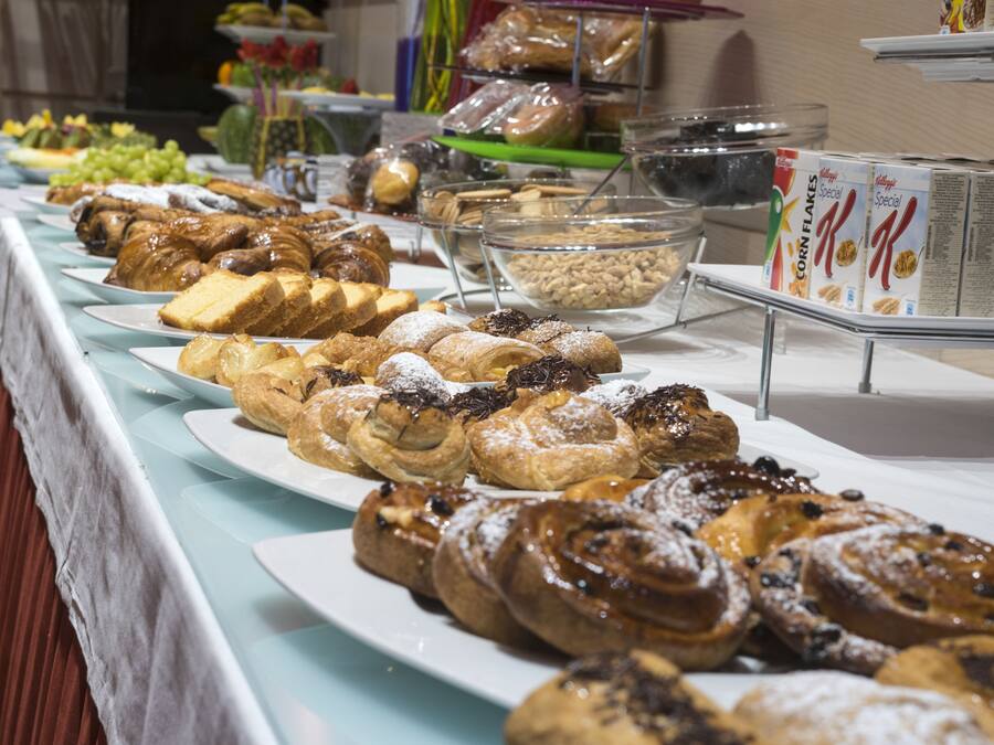 Een buffet met diverse gebakjes en ontbijtgranen in dozen.