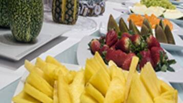 A buffet with various fruits and vegetables, including pineapple, strawberries, and carrots.