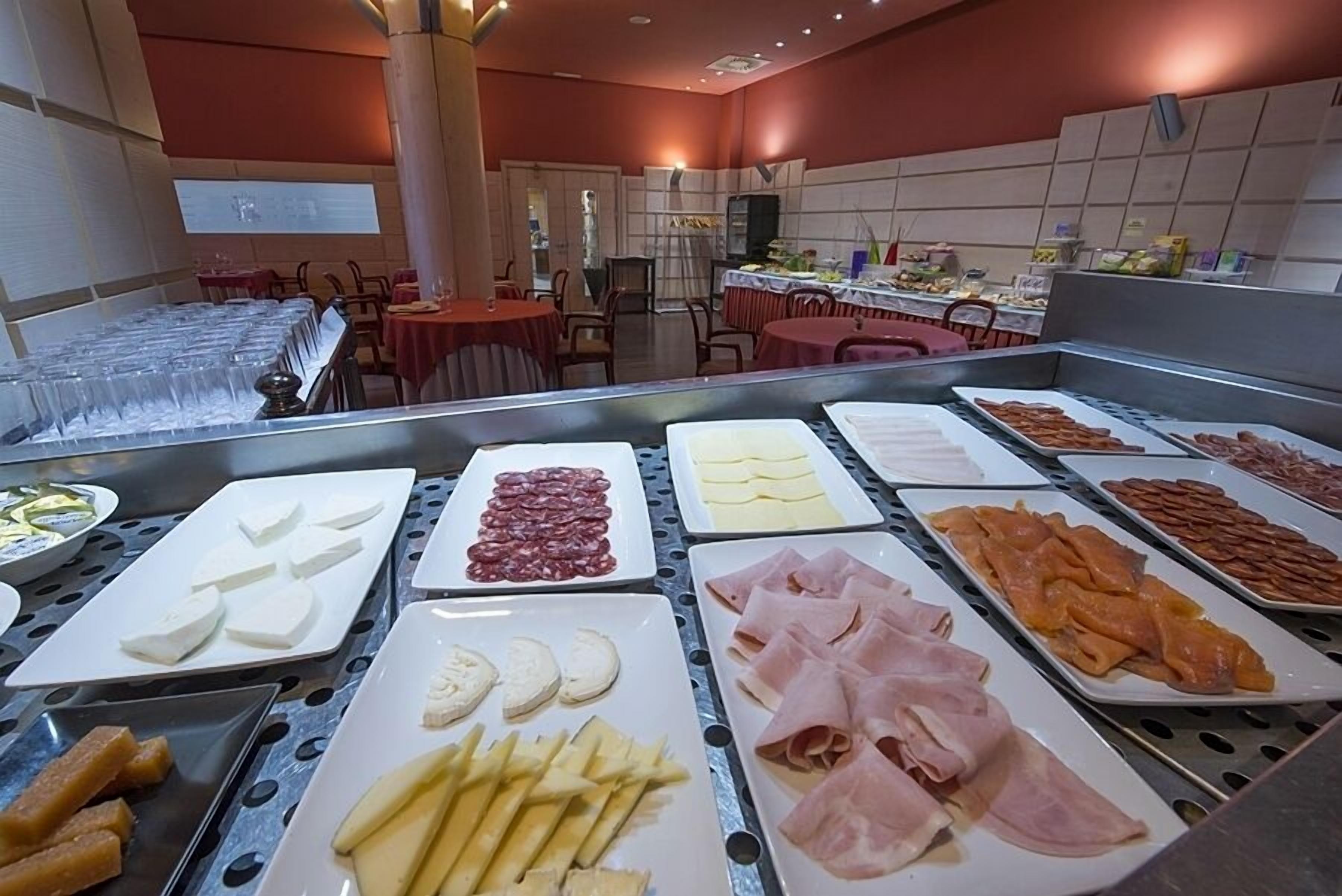 Un bufé con diferentes opciones de comida, incluyendo quesos, embutidos y frutas.