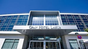 Exterior del Gran Hotel Laguna, con fachada moderna de vidrio y una entrada destacada.