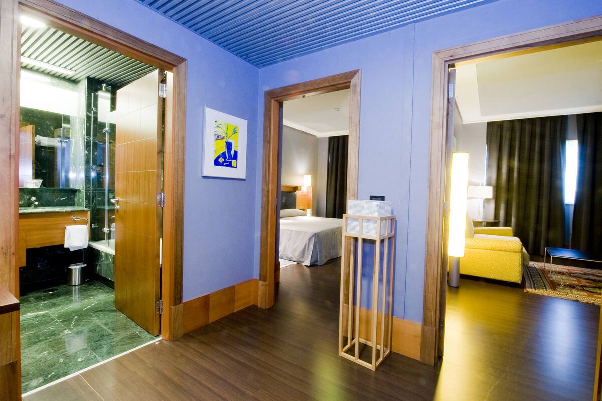 A hotel room with a bathroom, a bed, a bedside table, and a nightstand.