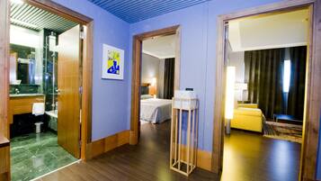 Una habitación de hotel con baño, una cama, una mesita de noche y un tocador.