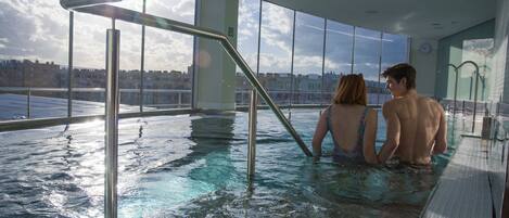 An indoor swimming pool with clear views of the cityscape through large windows.