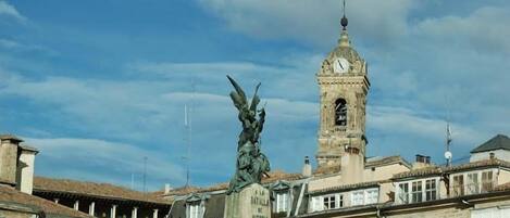 A historic building with a clock tower and a statue in front.