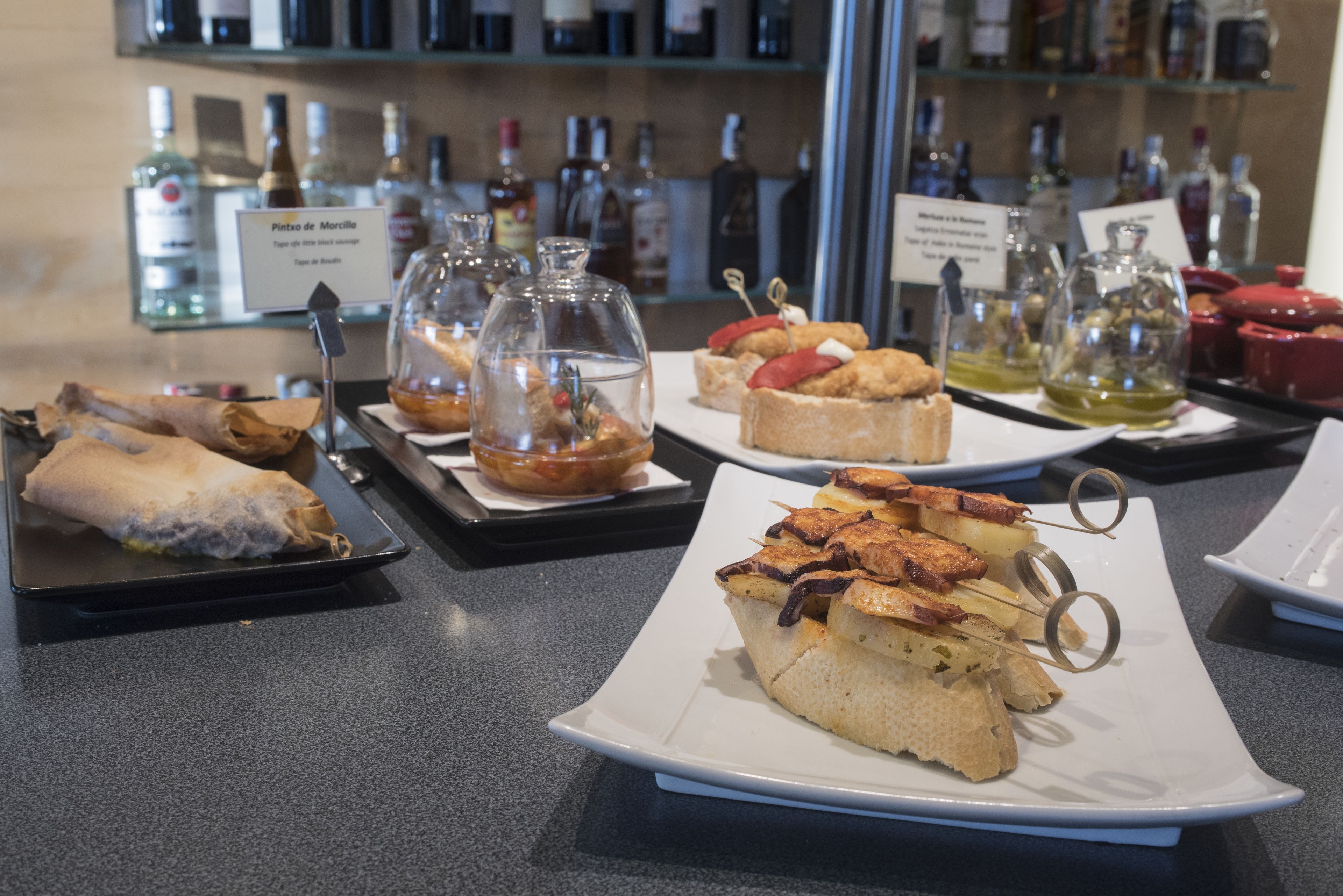 A buffet with various dishes and a selection of liquor bottles in the background.