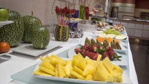 Un bufé con diversas frutas y verduras, entre ellas sandía, piña y fresas.