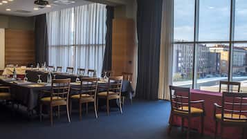 Un salón de conferencias con una gran mesa, sillas y vistas a edificios a través de amplios ventanales.