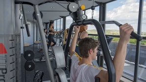 Un gimnasio con equipo de ejercicio, ventanas amplias y vistas al exterior.