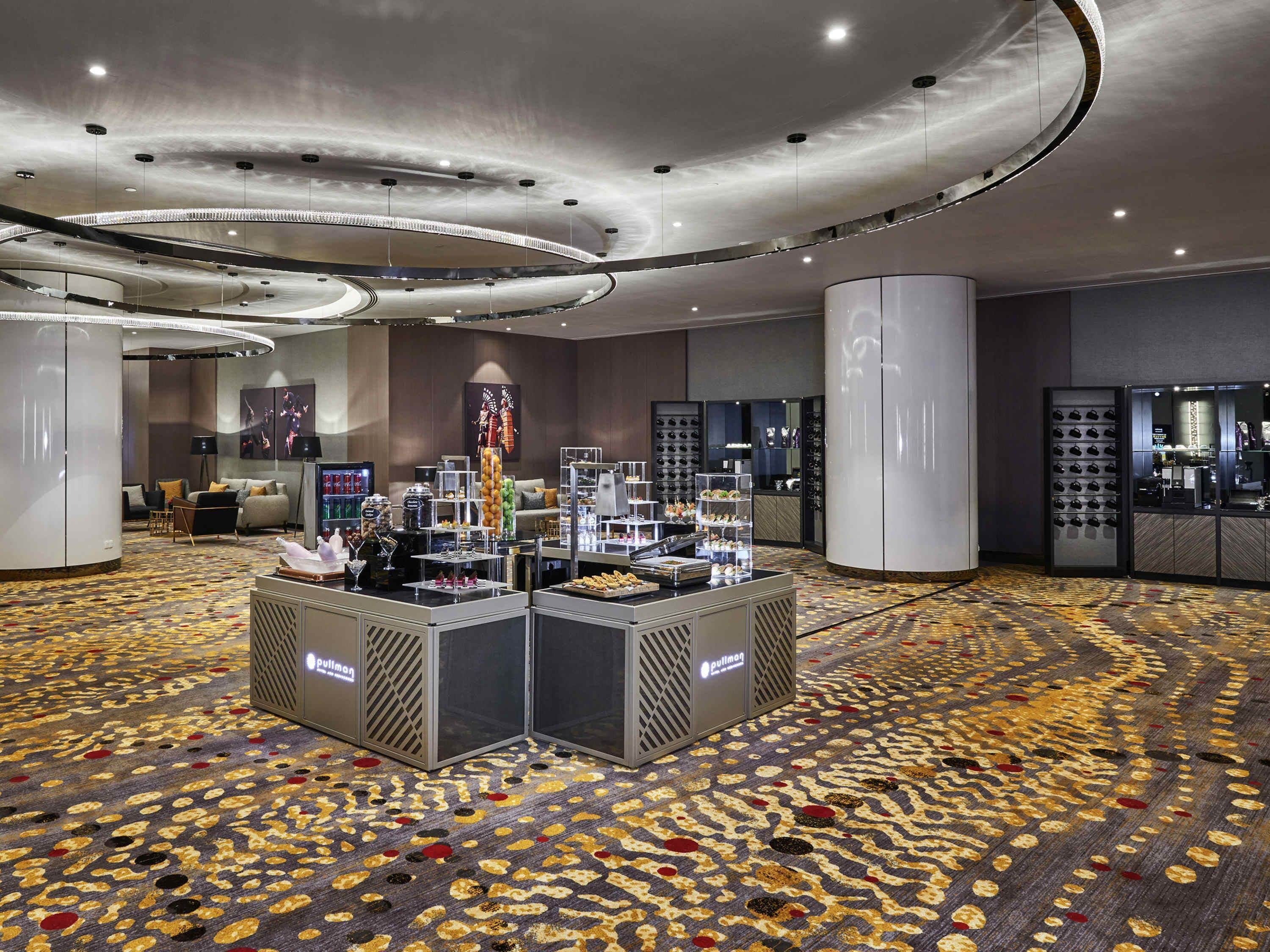 Een hotel lobby met een centraal etalage voor eten, een zithoek en een schoenpresentatie.