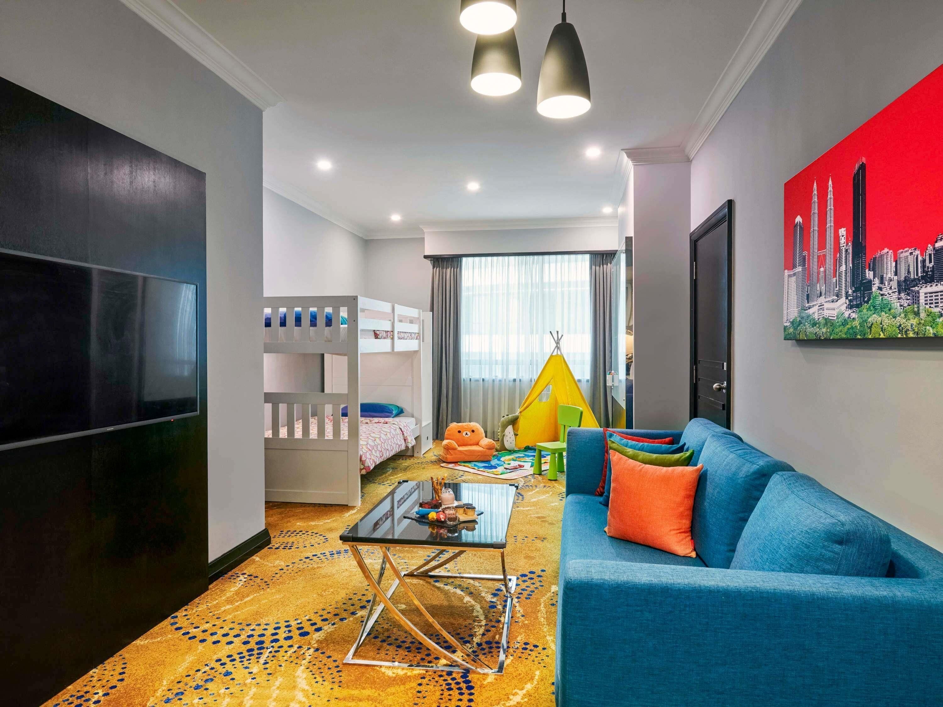 A modern living room with a TV, bunk beds, a sofa, a coffee table, and a cityscape painting.