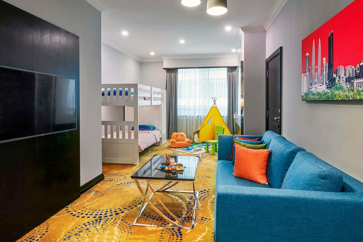 A modern living room with a TV, bunk beds, a sofa, a coffee table, and a cityscape painting.