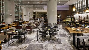 A modern restaurant with marble flooring, multiple dining areas, and a bar with a variety of food displays. - Pullman Kuala Lumpur City Centre Hotel & Residences (Kuala Lumpur)