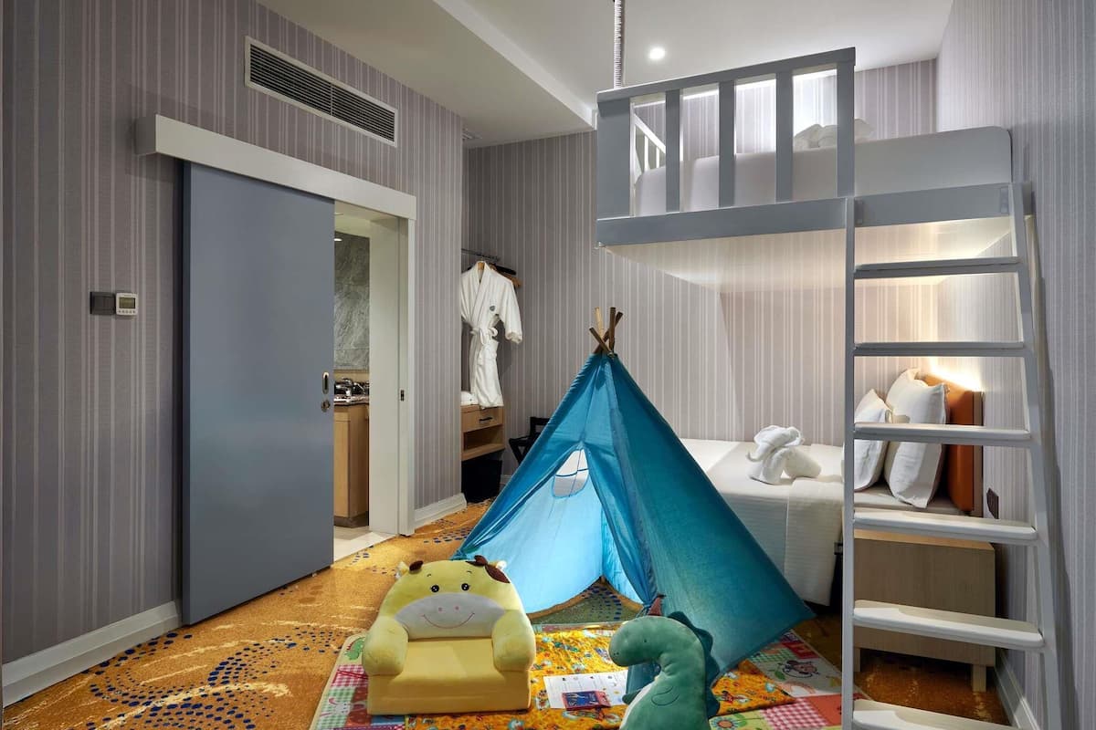 A child's room with a bunk bed, a tent, a toy dinosaur, and a colorful play mat.