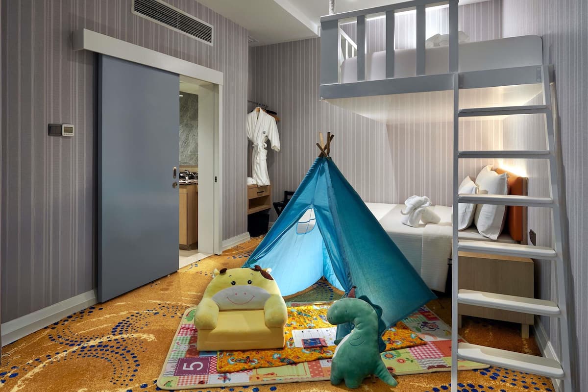 A child's room with a bunk bed, a tent, a toy dinosaur, and a small sofa.